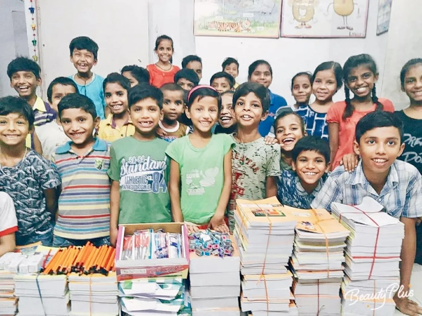 Children gathered with piles of notebooks and stationery on distribution day