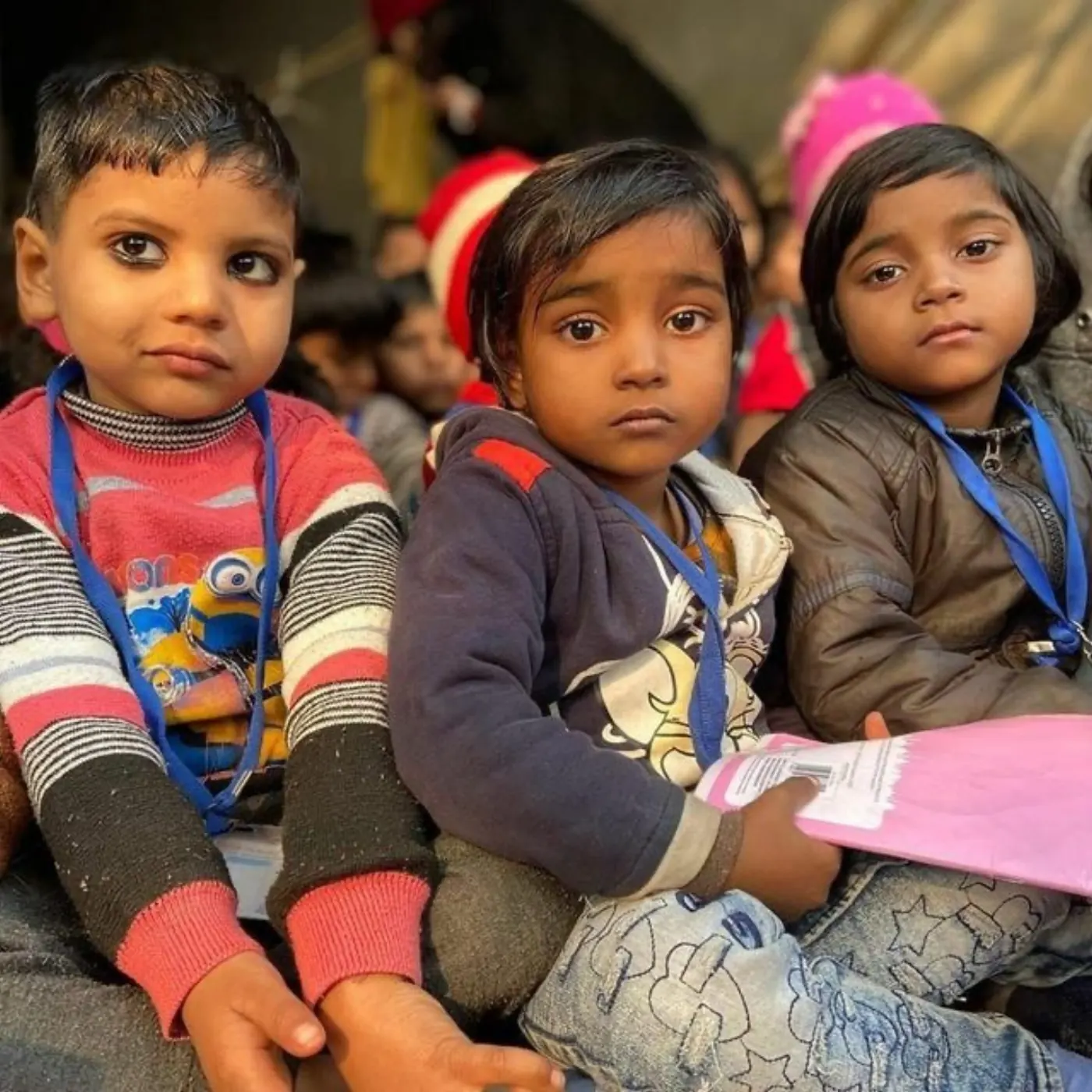 Three little children sitting together at a community event