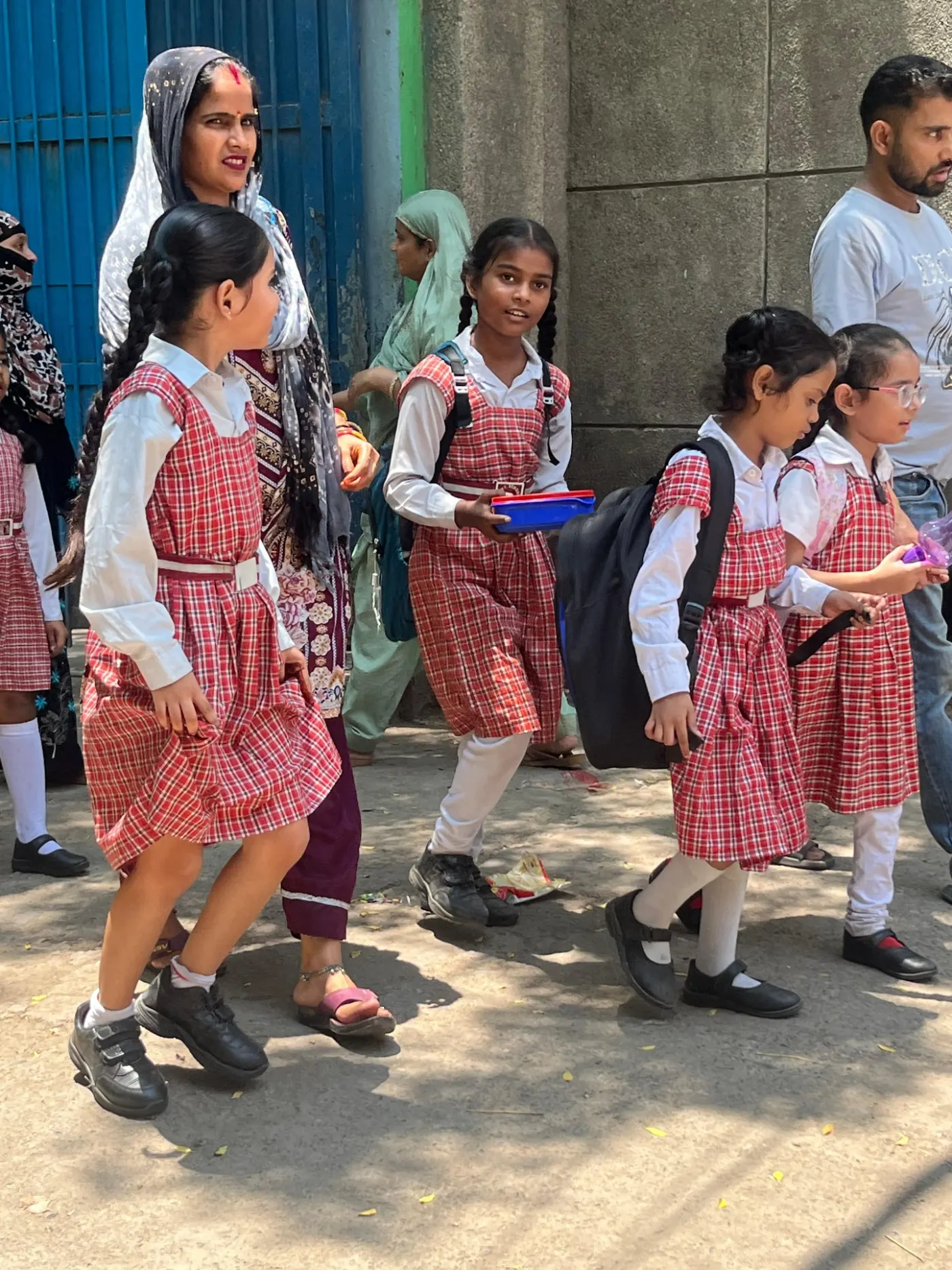 Group of girls in red uniforms walking to school with their mother