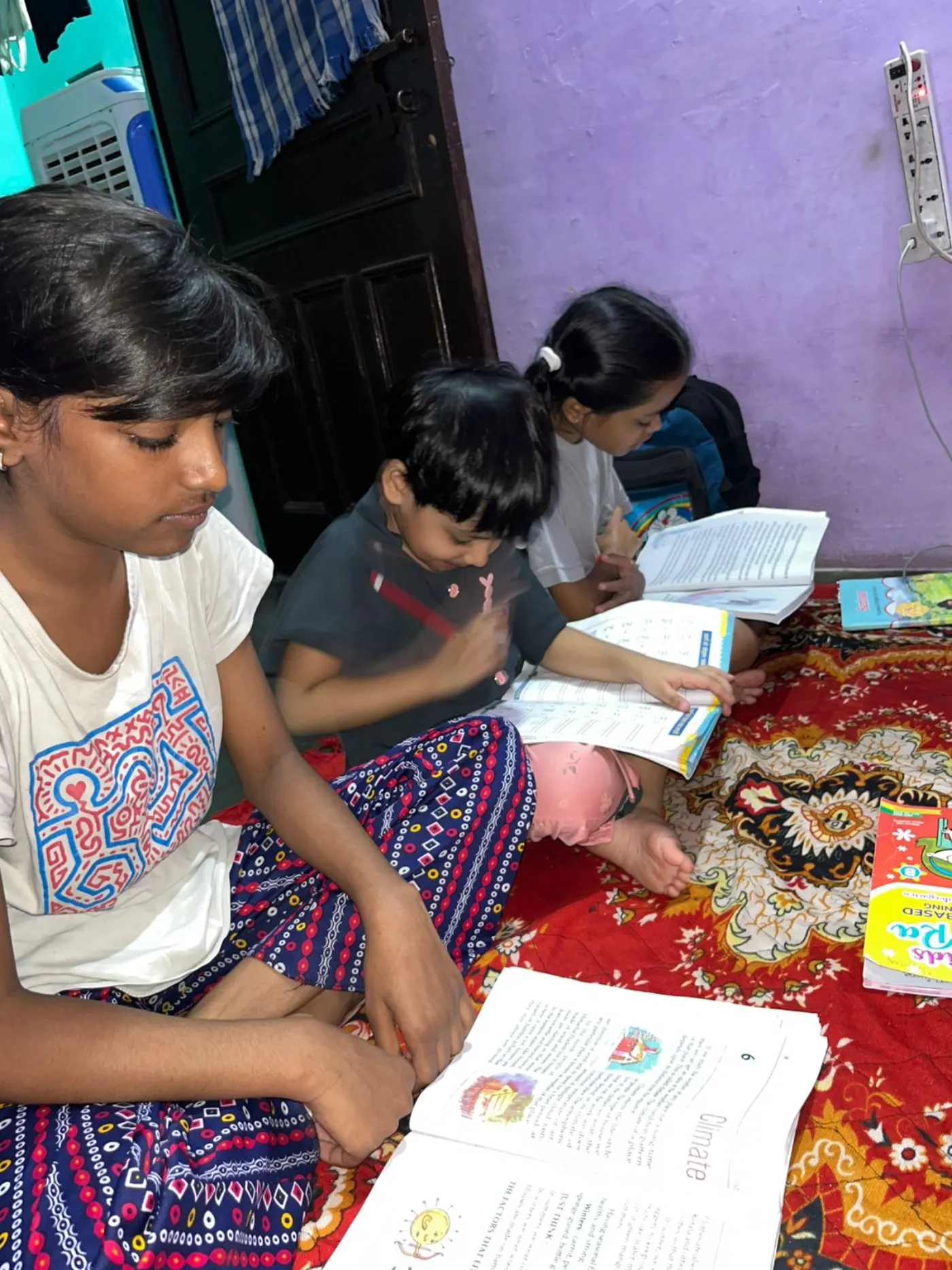 Three children studying together on the floor at home