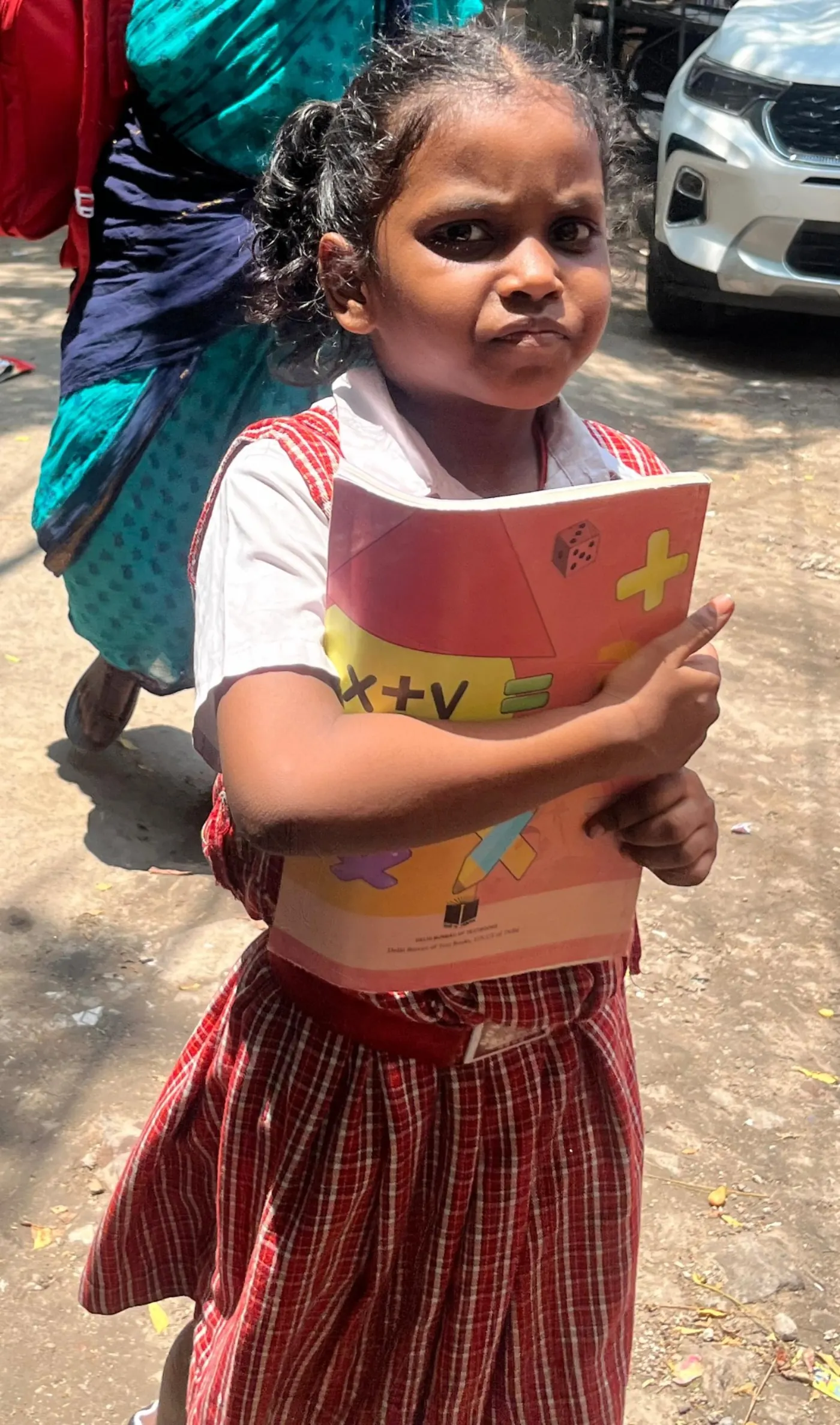 Young girl holding her mathematics workbook close