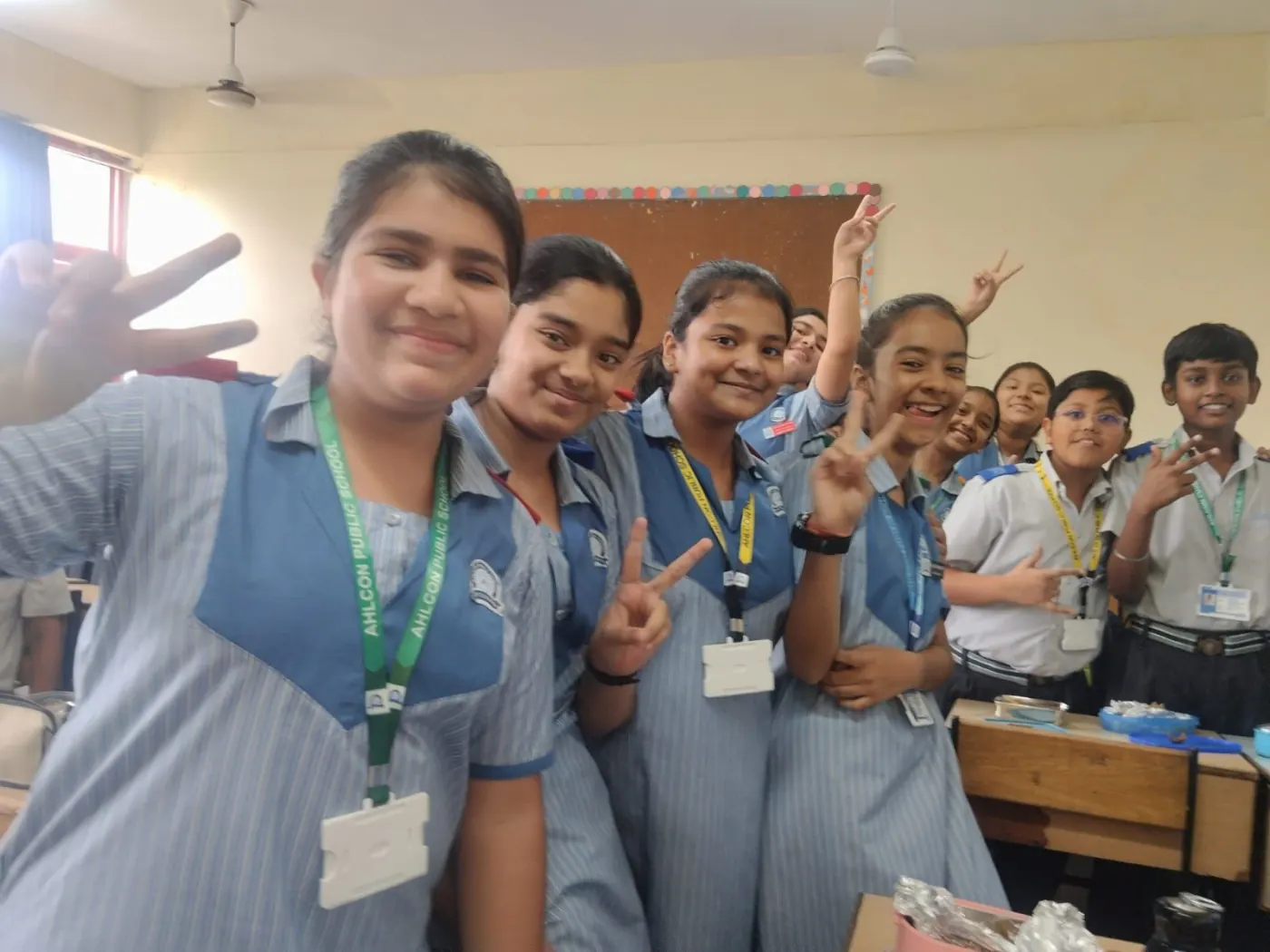 School girls flashing peace signs in a classroom selfie